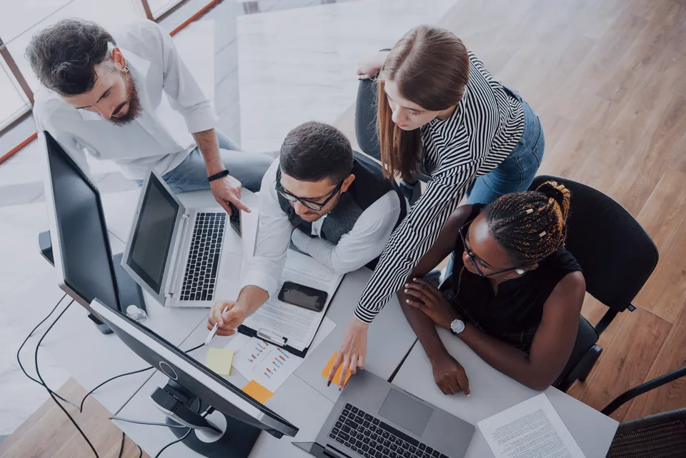 Equipe analisando documentos e notebooks em uma mesa